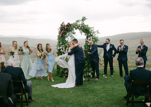 A couple share their first kiss as man and wife on a rare rainy day on a ranch wedding venue.