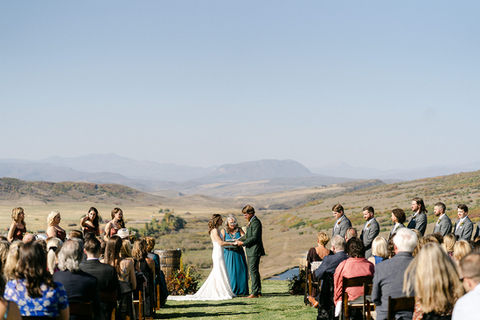 A couple get wedded along side family and friends looking over beautiful Colorado mountain at a Steamboat wedding venue.
