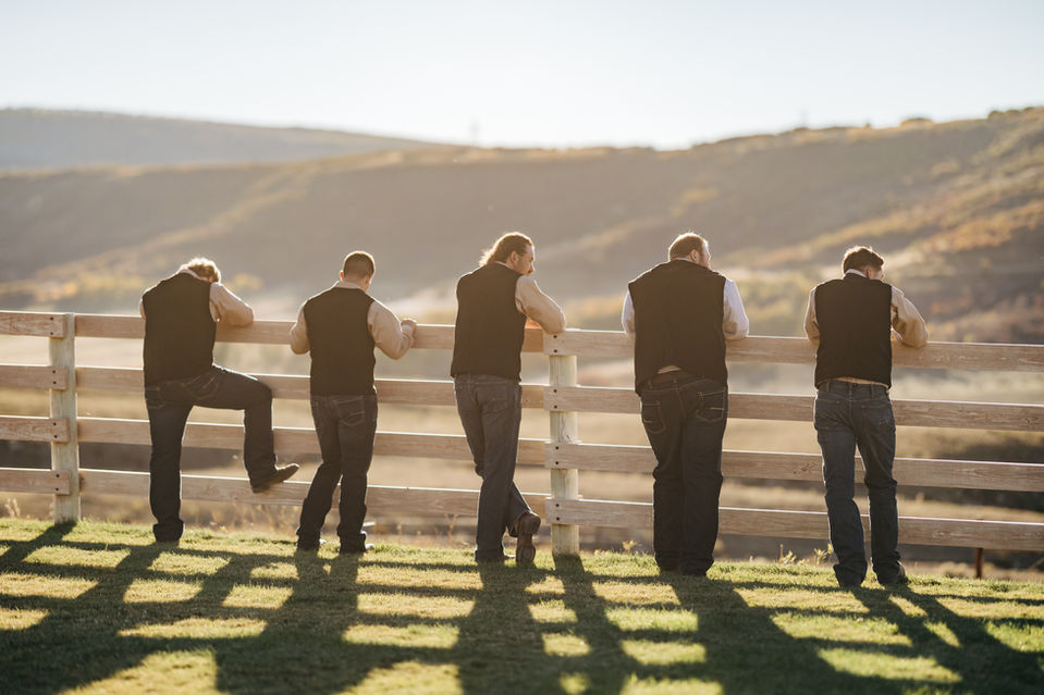 A groom relaxing with his men while his bride is taking photos.