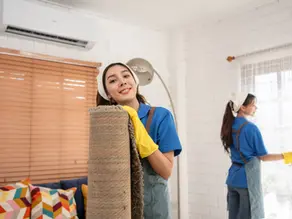 Smiling cleaning lady holding feather duster in warehouse
