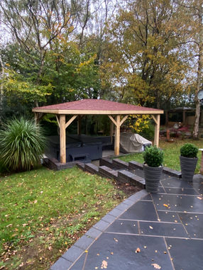 Wooden gazebo with sides open in a landscaped garden