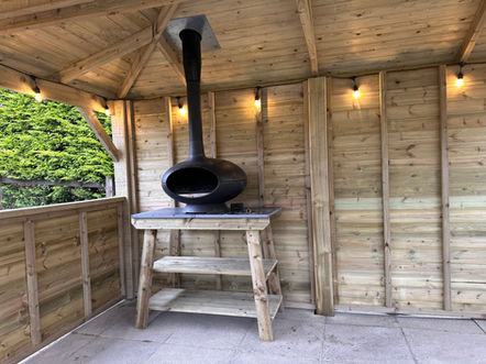 Small pizza oven under a timber gazebo with full height solid rear panels.