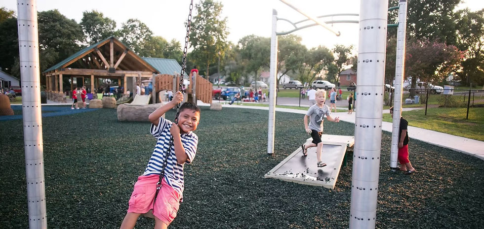 A smiling young boy swings at the Blythe Oldfield Park.