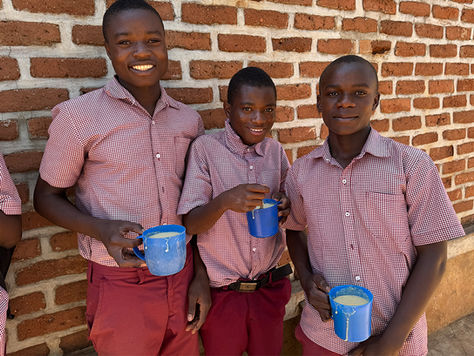 Three schoolboys in Hope Secondary School uniform with mugs of phala porridge