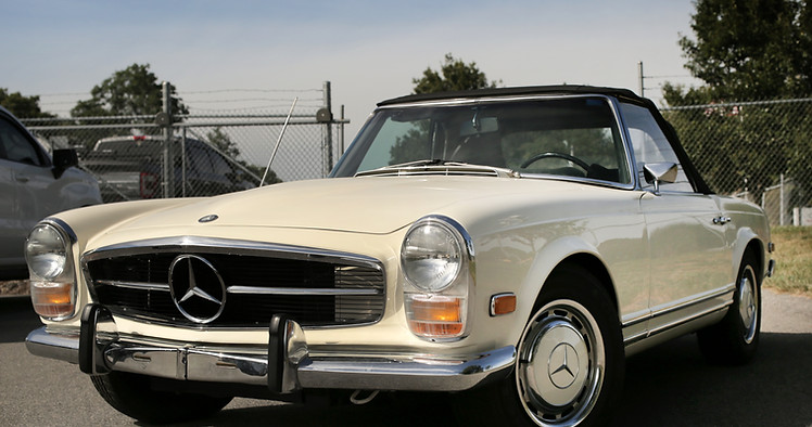 Front view of a cream Mercedes-Benz W113 Pagoda SL convertible with black soft top at Angels Touch Restoration.
