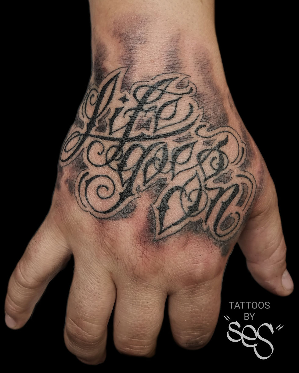 Custom Chicano style script lettering tattoo on hand by Ses at Blackwork Tattoo Studio in Little Falls, NJ