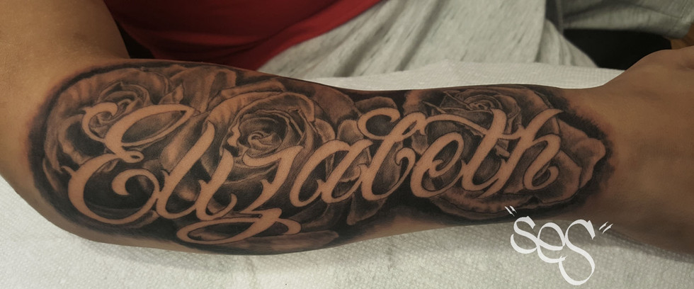 Custom Chicano style script lettering and roses tattoo  by Ses at Blackwork Tattoo Studio in Little Falls, NJ