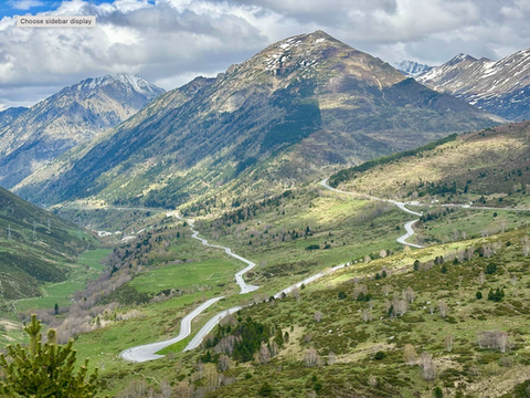Green valley and sweeping road climbing into Andorra through the Pyrenees, part of the legendary N-260 route.