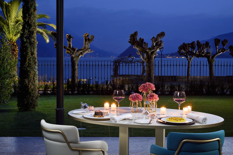 Romantic restaurant terrace at a Lake Como hotel, with candlelit tables and lake view at dusk.