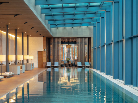Indoor pool at The Chedi Andermatt with floor-to-ceiling windows and serene views towards the surrounding mountains.