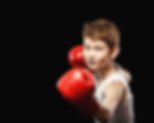 Young boy wearing red boxing gloves in a fighter stance.