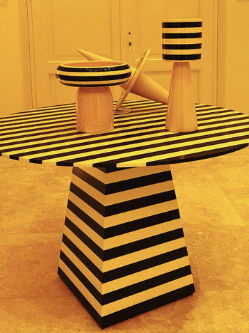 Mesa y objetos decorativos con diseño a rayas blanco y negro sobre piso amarillo - TW Buenos Aires
