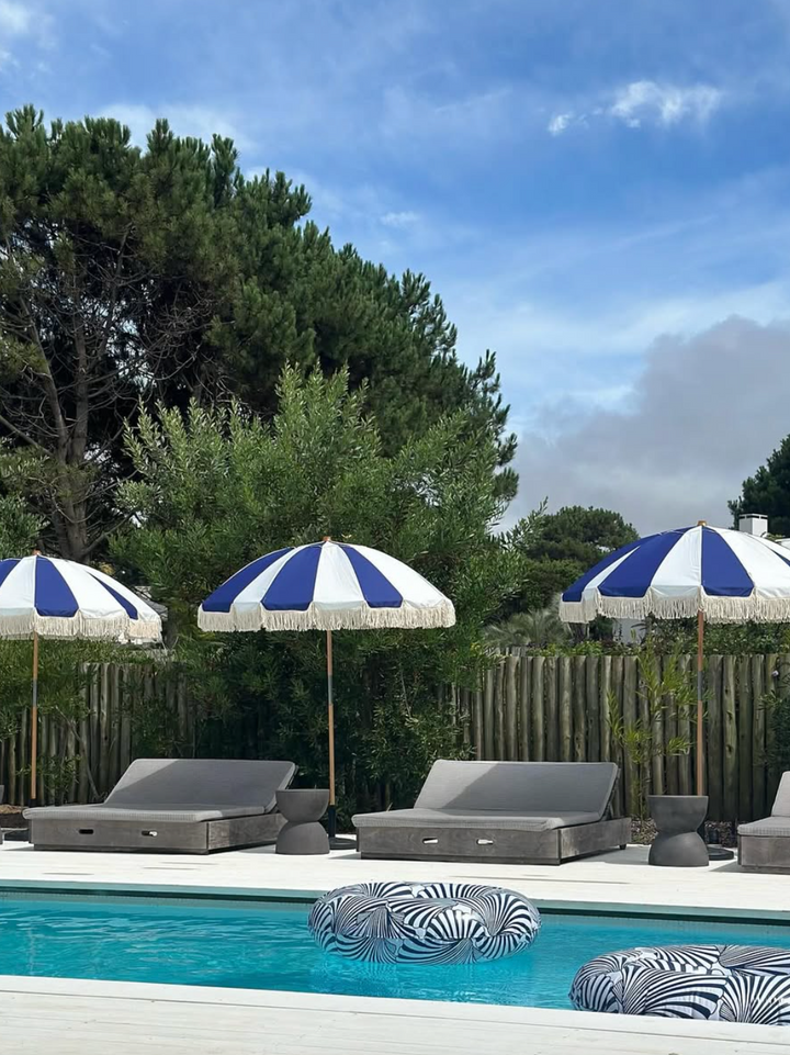 Sombrillas azules y blancas junto a piscina en jardín - TW Buenos Aires