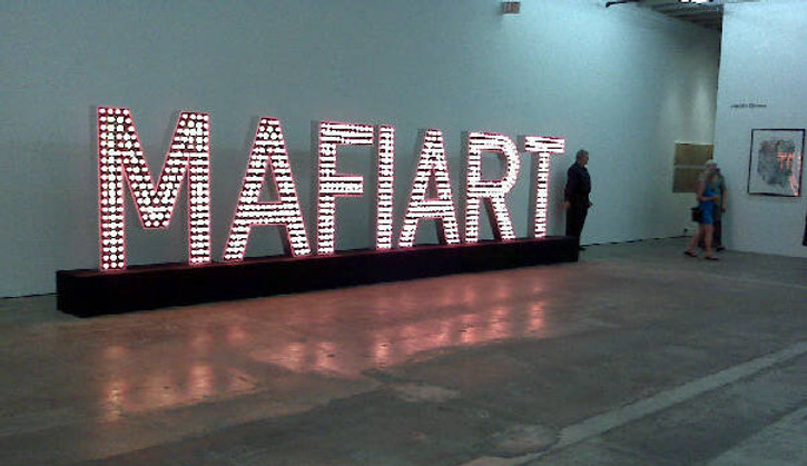 Mafiart is a work created by Klaus Guingand in 2009. Wood,metal & 852 Red & yellow flashing light bulbs 314 x 12 x 86,6 in. Mafiart TM © Klaus Guingand