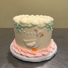 Smash cake decorated with a duck, pink ruffles, and teal trim