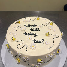 Baby shower cake with 'what will baby bee?' text, bees, and daisies