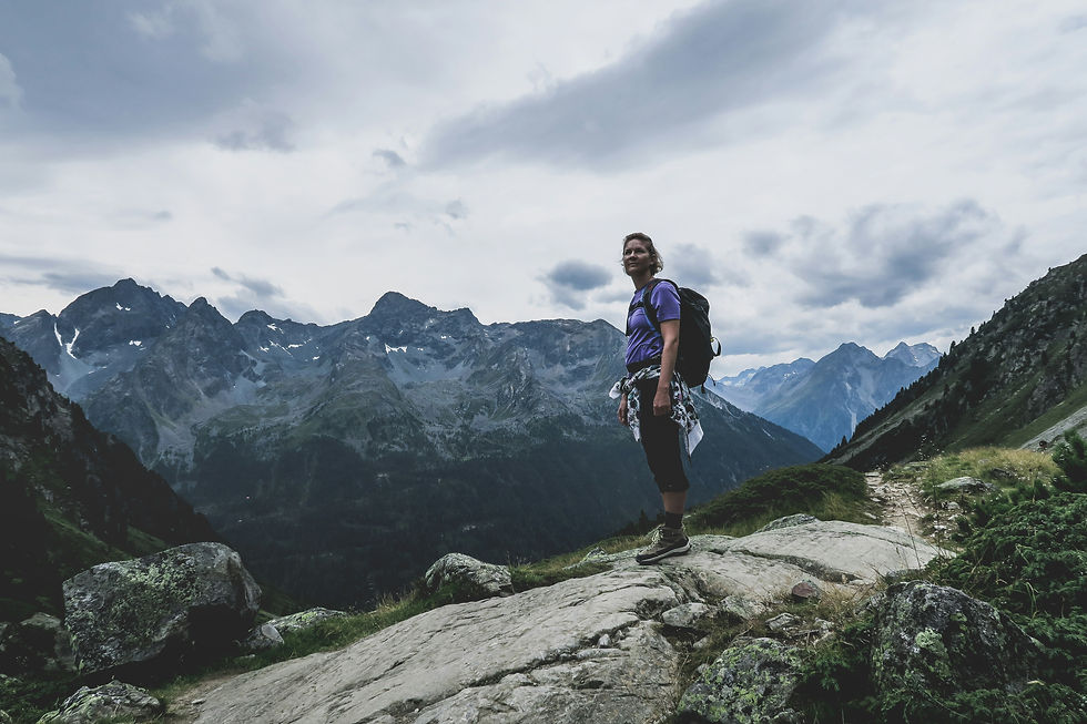 A woman in a purple t-shirt poses for a photo while hiking the trails of Chamonix, France. Equipped with proper hiking shoes, she embodies the essence of summer exploration in the Alps. ALPY travel guide emphasizes the importance of wearing suitable footwear for safe and enjoyable hiking experiences in the Alpine terrain.