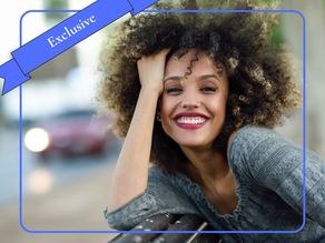 Alt text: "Woman smiling and leaning against a railing outdoors, reflecting the sense of joy and enthusiasm associated with using a personal character strength.