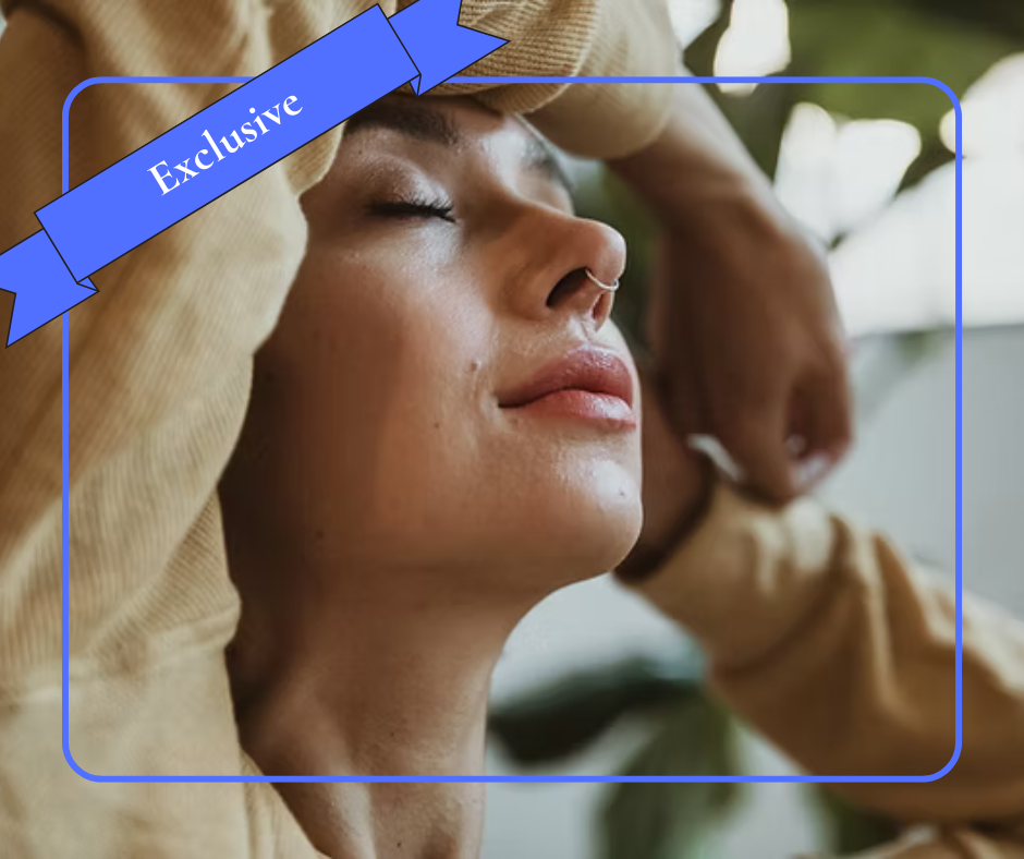 Woman pausing with eyes closed, arms raised, reflecting a moment of grounding to interrupt overwhelm.