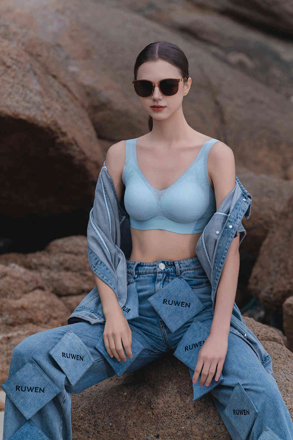 Thumbnail: Ruwen New Spring Lace vest in baby blue colour worn by a model sitting down on the rock with jeans