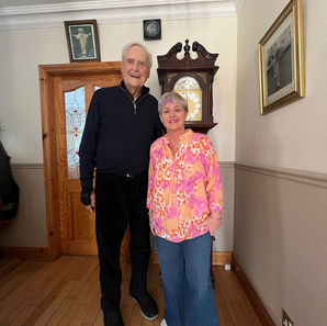 “91 year old homeowner Mick standing smiling beside his Home Share companion Brenda in his home in Ireland, showing companionship, support and independent living in later life.”