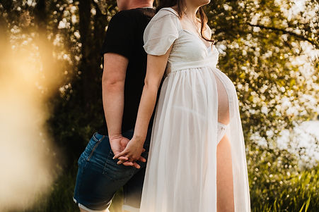 Schwangerschaftsshooting mit dem Partner im Licht der untergehenden Sonne
