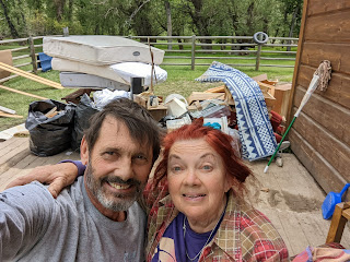 In work clothes and tired, Bruce Keller and Christene "Cookie" Meyers pause after helping neighbors remove furniture and debris in preparation for redoing a beautiful guest house on the Stillwater River, which produced record water.