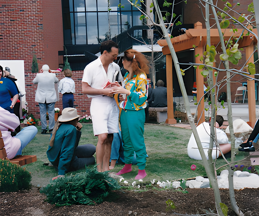 Corby Skinner and Christene meyers embrace in a the couryard of the Bruce Meyers Poets Garden at the dedication of the memorialg, surrounded by seated guests, brick walls, and pergola posts.