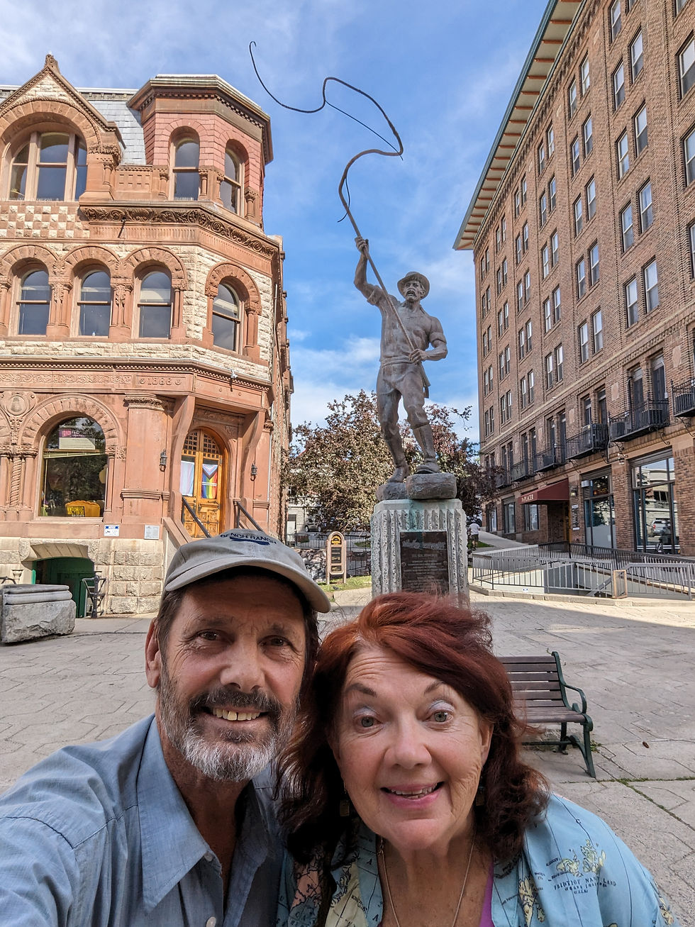 "Bullwhacker" stands in Helena's central plaza, surrounded by historic brick buildings The sculpture honors Helena’s early freight era, when oxen-pulled wagons hauled goods from Fort Benton to the growing mining town.