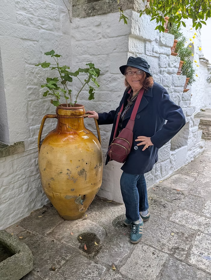 At a trulli home, Cookie poses by a planter, a century old urn in a centuries old town.