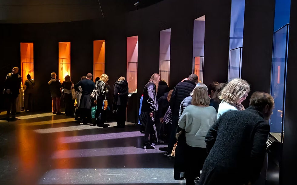 Visitors view colorful Cartier exhibits lit by orange, pink and blue window-like displays