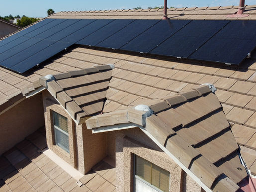 Phoenix homeowner comparing APS solar rate plans on laptop with solar panels visible on roof