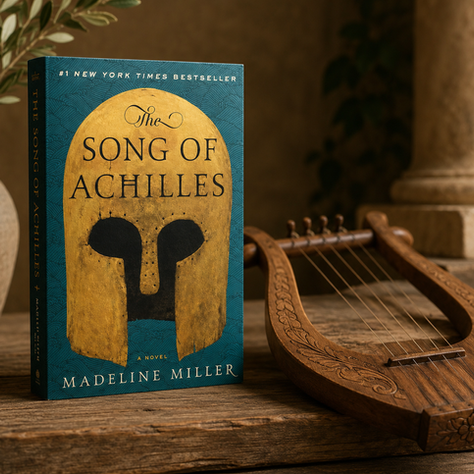 The Song of Achilles book cover beside a wooden lyre on a rustic table, with warm Greek-inspired decor.