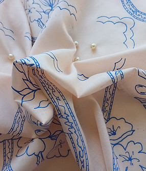 A close-up of Molina Sovereign in cream fine cotton, with screen printed surface pattern and embellishment.