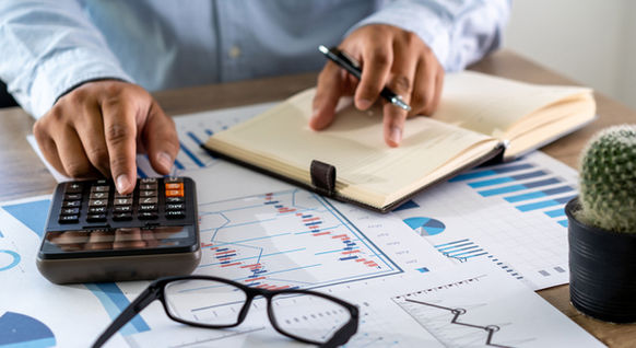 A financial professional uses various tools and spreadsheets at their desk.