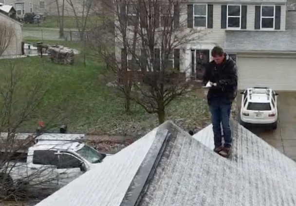 A RoofCo specialist standing on a frosty asphalt shingle roof taking notes during a pre-winter residential inspection in Central Indiana.