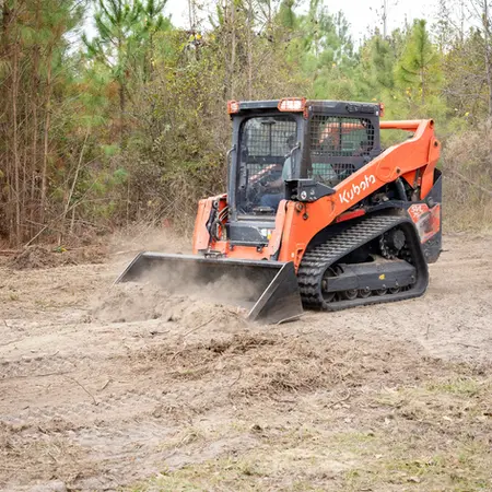 Land cleanup in progress with compact track loader on private property.