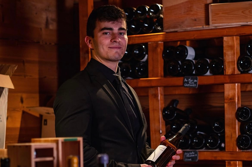 Noah Klement, sommelier and co-owner of Mineralienhotel Natznerhof, presenting a wine bottle in the hotel's wooden wine cellar, South Tyrol