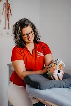 Katharina Kremmer hält ein Schädelmodell in den Händen und zeigt Craniosacral Behandlung