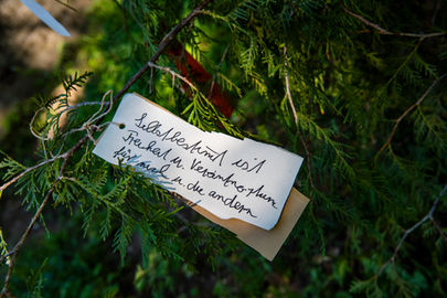 Ein handgeschriebener Zettel an einem Ast befestigt. Text: "Selbstbestimmt ist Freiheit und Verantwortung für mich und andere