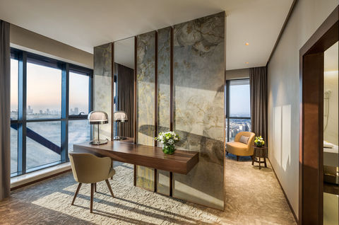 Modern luxury hotel room with desk, mirrors, and city view.