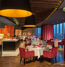Luxury restaurant dining room with warm lighting and deep red accents.