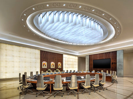 Conference room interior at Qasr Al Watan, Abu Dhabi, featuring an oval table, ergonomic chairs, dark wood paneling, and backlit ceiling light