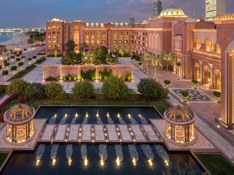 Emirates Palace with illuminated fountains and beach at dusk
