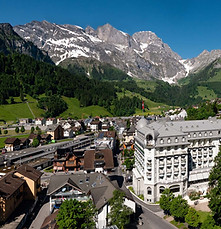 Aerial view of Engelberg alpine village in Switzerland with Kempinski Palace Engelberg overlooking the green valley.