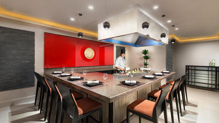 Chef preparing food at a teppanyaki restaurant table.