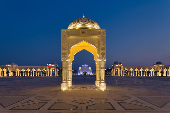 Exterior of Qasr Al Watan, Abu Dhabi, with a brightly lit ornate archway framing the palace in the background.