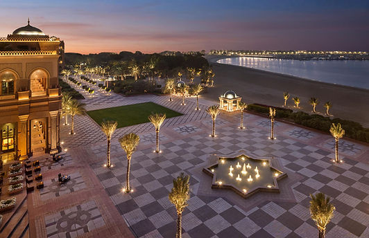 Illuminated exterior courtyards and beachfront promenade of the luxurious Emirates Palace Mandarin Oriental in Abu Dhabi, UAE.