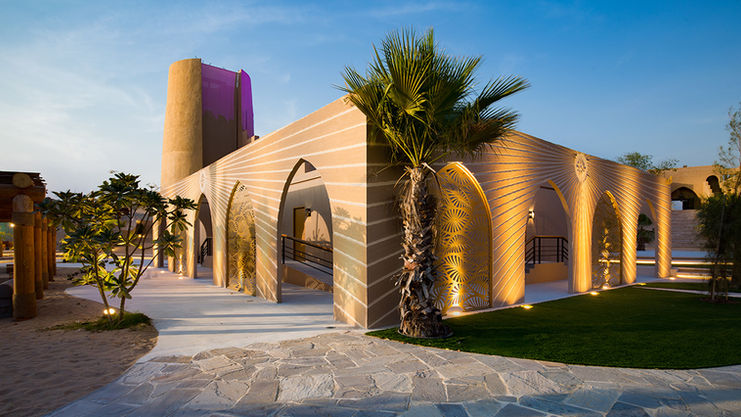 Terra Solis Dubai resort exterior with lit arches and cylindrical tower in the desert