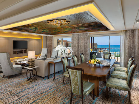 Luxury hotel suite with dining and living area, ocean view.
